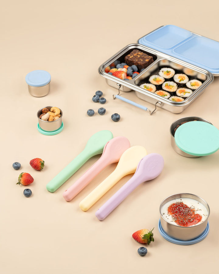 Set of colorful spoons and a bento box with food on a beige background baboons tiffin India