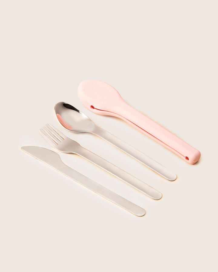 Flat lay of reusable stainless steel cutlery set with blush pink silicone carry case by Baboons India.
Child using reusable stainless steel cutlery with silicone case during school tiffin lunch by Baboons in India.