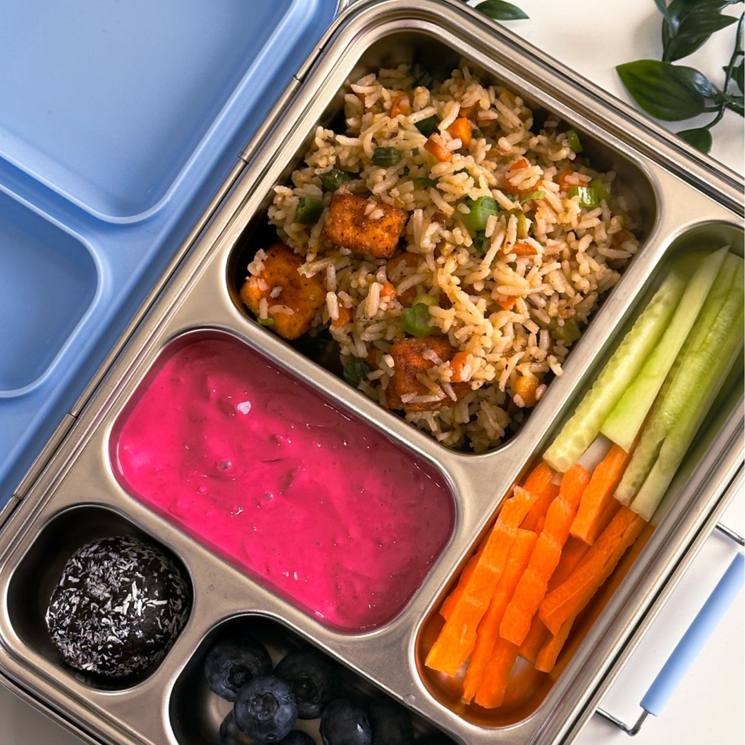Stainless steel bento lunchbox packed with paneer fried rice, beetroot raita, fresh veggie sticks, energy ball, and blueberries – healthy Indian lunchbox idea for kids.