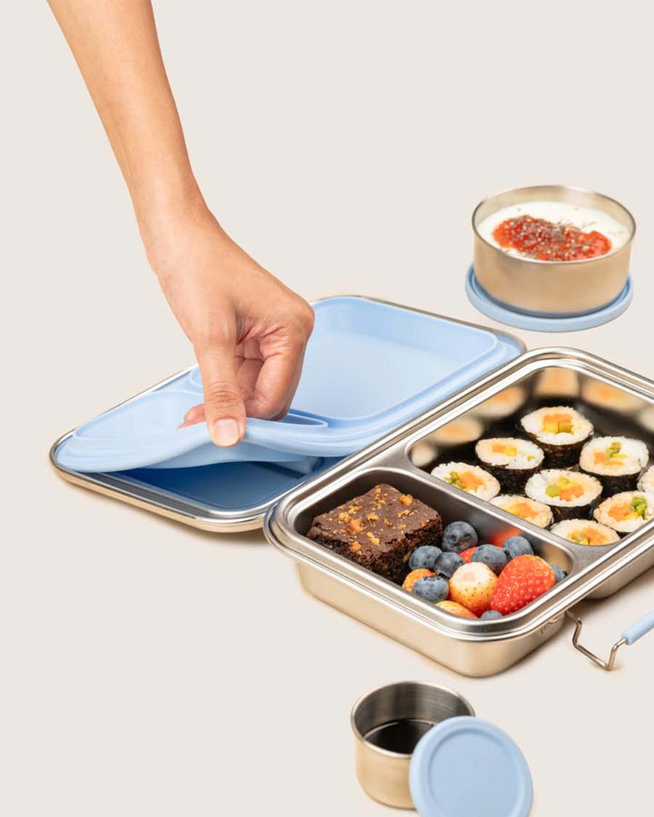 Lifestyle view of Baboons Bento Two Frost Blue leakproof lunchbox with sushi, fruit, brownie, and snack boxes.