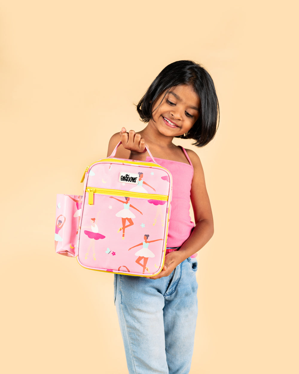 Smiling girl holding Baboons insulated kids lunch bag - ballet pink, durable, water-resistant, perfect for bento boxes and snacks, available in India