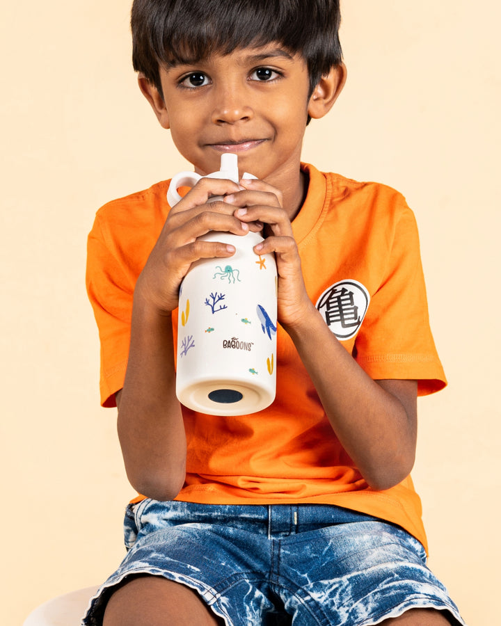 Indian boy drinking from a 350ml ocean theme stainless steel water bottle with sipper straw lid and silicone bumper, perfect for kids' school and outdoor activities.