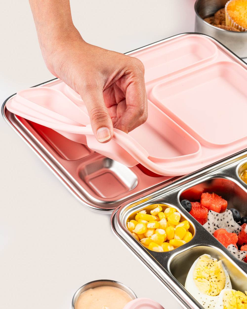 Bento Five stainless steel lunchbox with pink silicone compartments, showing silicone removal and food compartments