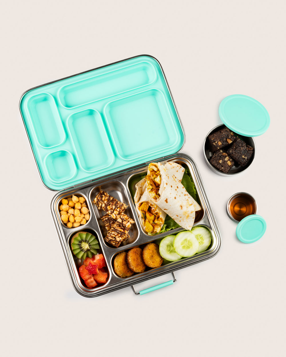 A reusable stainless-steel lunchbox in aqua packed with a delicious Indian meal, including a variety of fruits, vegetables, and snacks.