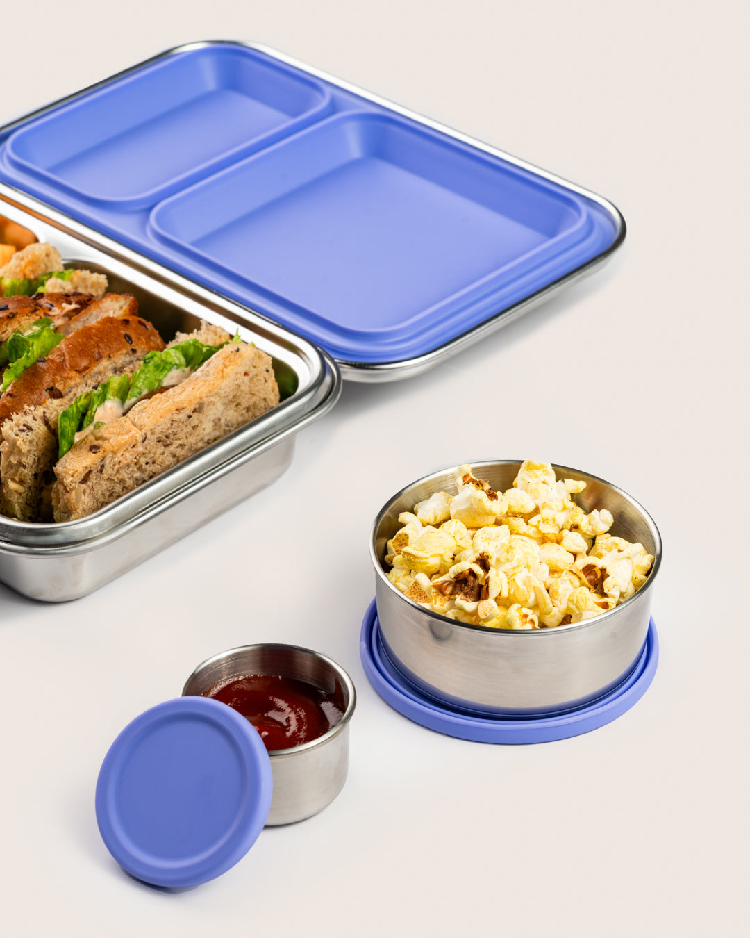 Leakproof purple snack container set with silicone lids, featuring a large container with popcorn and a small container with sauce, ideal for carrying snacks in India